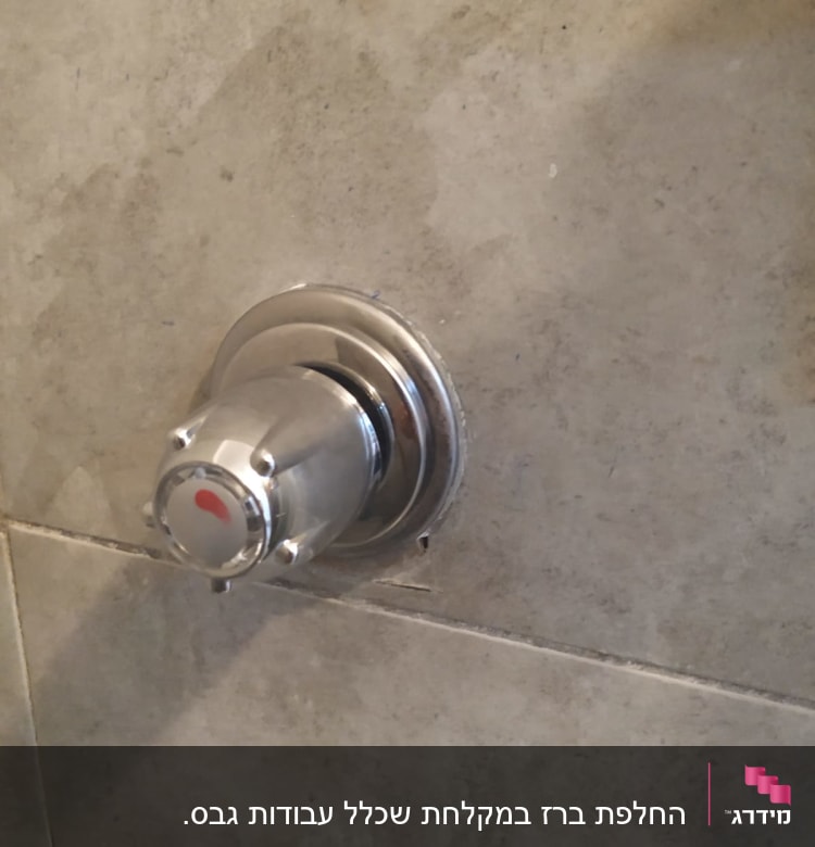 ברז מים מתכת על קיר אריחים